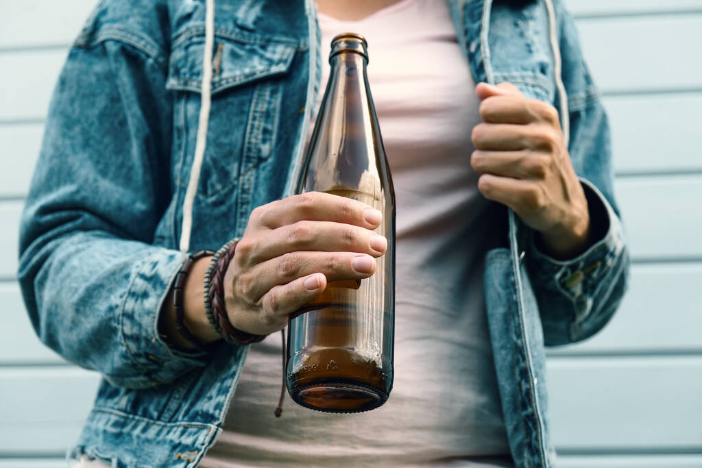 Een dronken vrouw gekleed punk, informeel bier drinken uit een bruine fles, alcohol overdosering en verslaving concept. - Foto, afbeelding