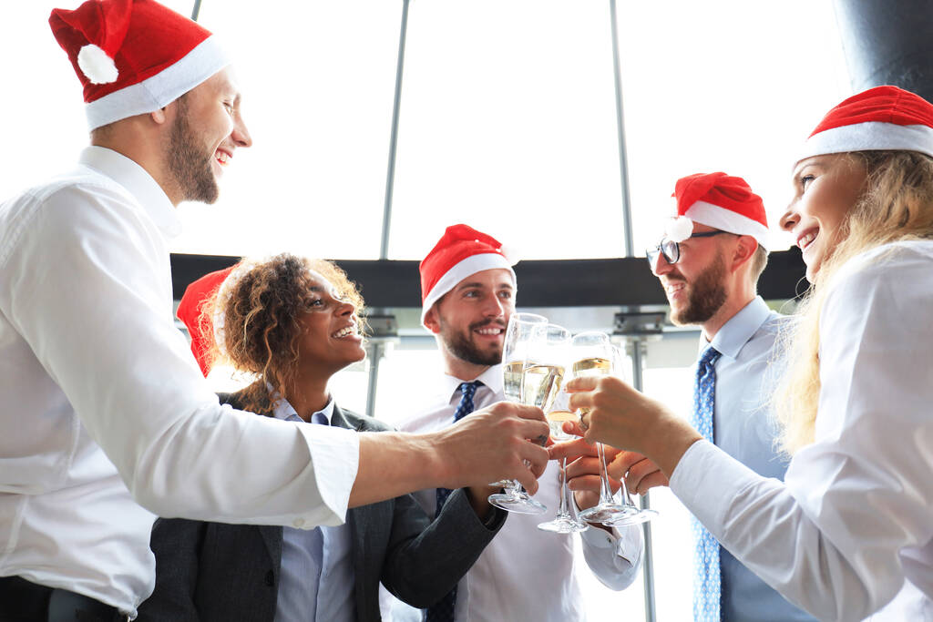 Compañeros de trabajo de oficina celebrando vacaciones de invierno juntos en el trabajo y bebiendo champán en la oficina. Feliz Navidad y Feliz Año Nuevo - Foto, imagen