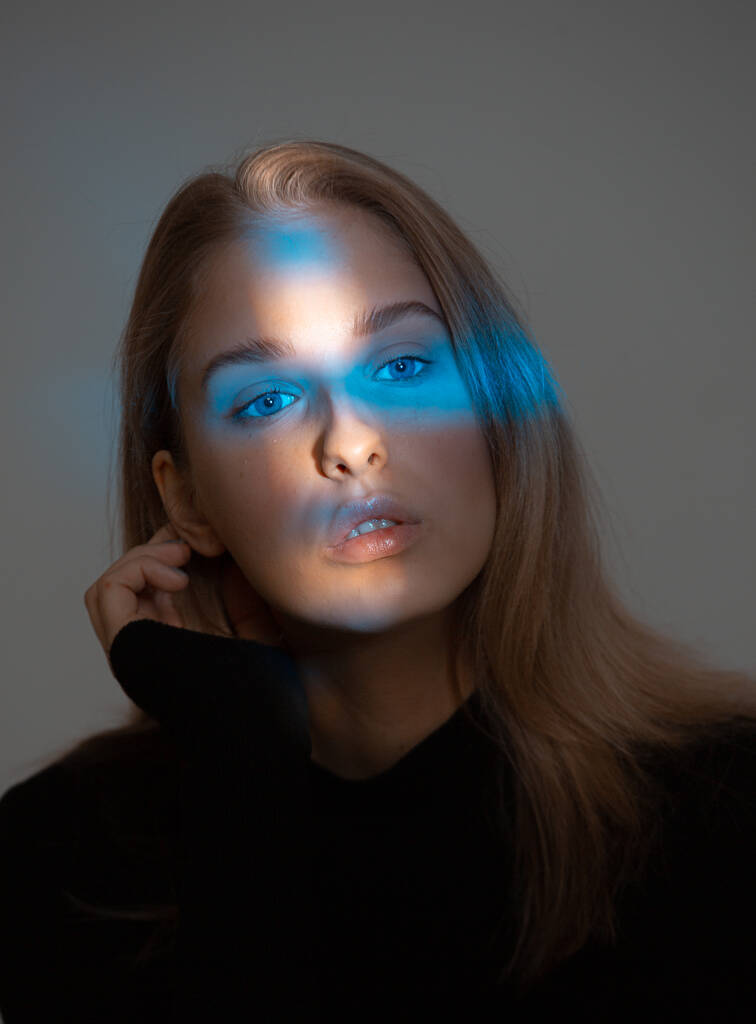 Δημιουργικό πορτραίτο στούντιο της κομψής νεαρής κοπέλας με μπλε νέον φως στο πρόσωπό της και τέλειο δέρμα - Φωτογραφία, εικόνα