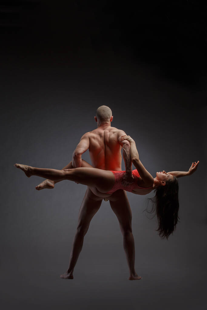 Пара танцоров в элегантной позе сзади на тёмном фоне. - Фото, изображение
