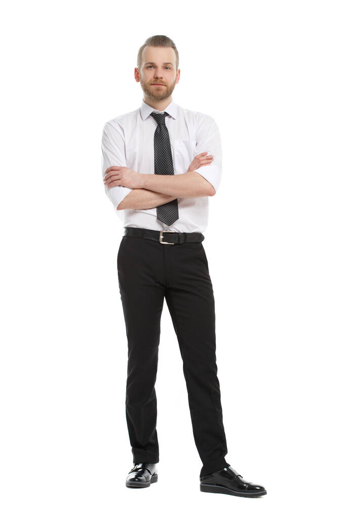 Un joven con barba en su camisa de diario está en pleno crecimiento, con los brazos cruzados, aislado sobre un fondo blanco. - Foto, imagen
