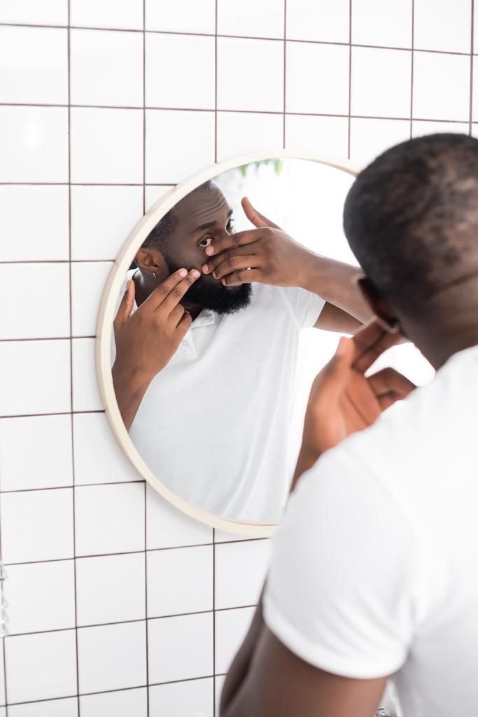hombre afro-americano tratando de apretar espinilla - Foto, Imagen