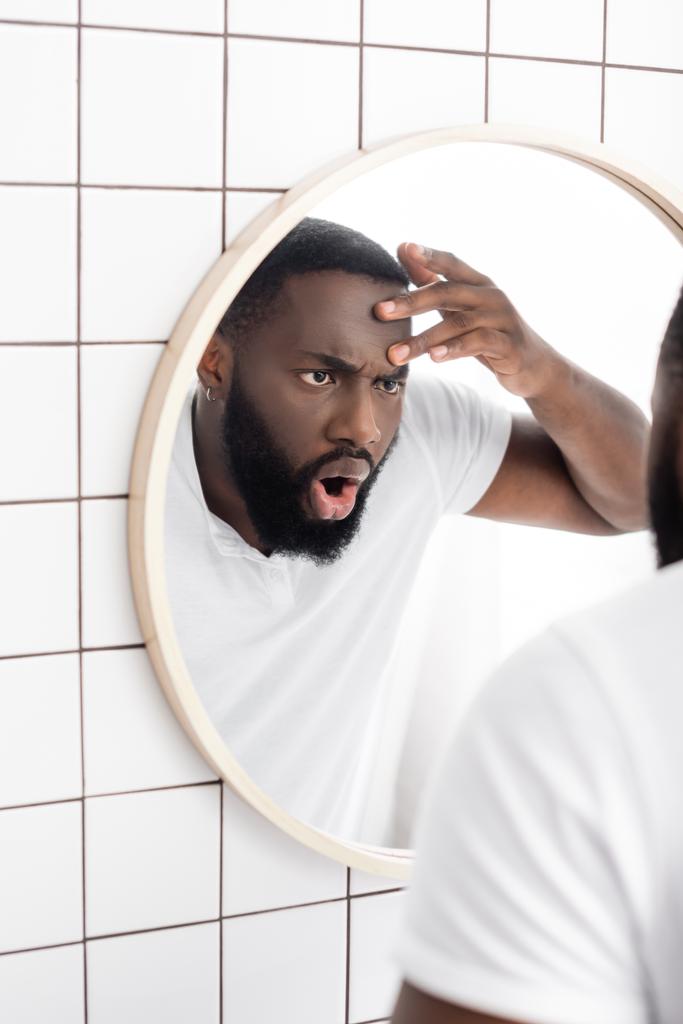 Geschockter Afroamerikaner sieht Falten im Spiegel - Foto, Bild