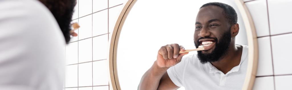 竹歯ブラシで歯を磨くアフロアメリカ人男性のパノラマ写真 - 写真・画像