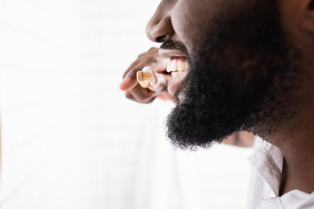 close-up view of afro-american man brushing teeth with bamboo toothbrush - Photo, Image