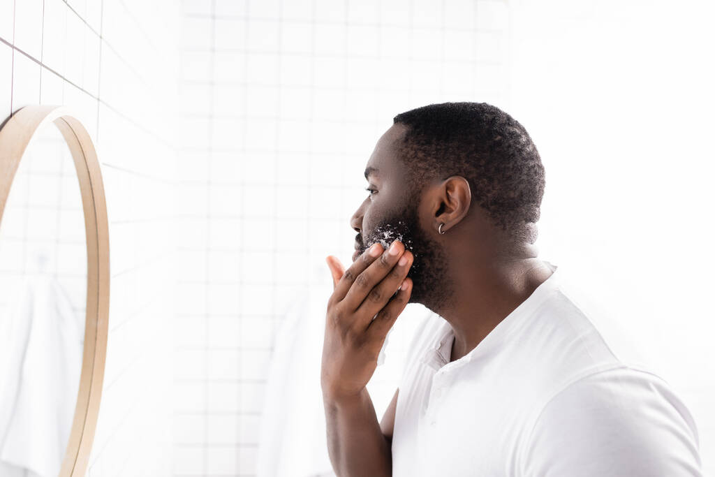 Afro-Amerikan bir adamın tıraş köpüğü sürüp aynaya baktığı yan manzara. - Fotoğraf, Görsel