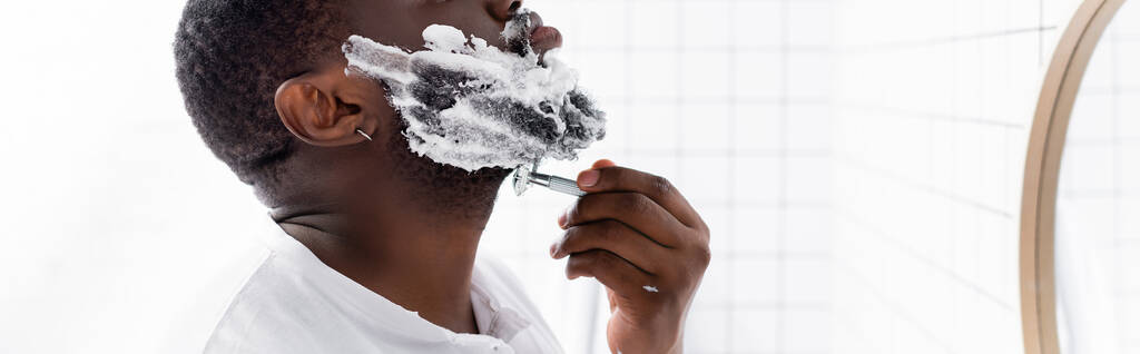 panoraama laukaus afroamerikkalainen mies parranajo parta partaveitsellä  - Valokuva, kuva