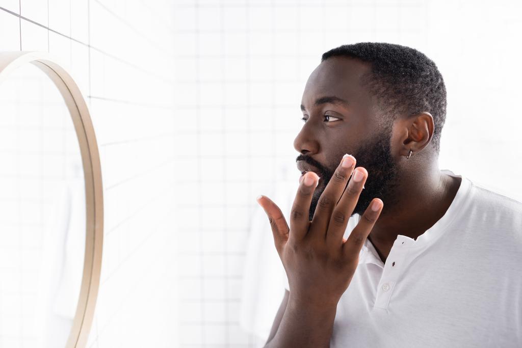 афроамериканський чоловік застосовує ліки для зміцнення росту бороди
 - Фото, зображення