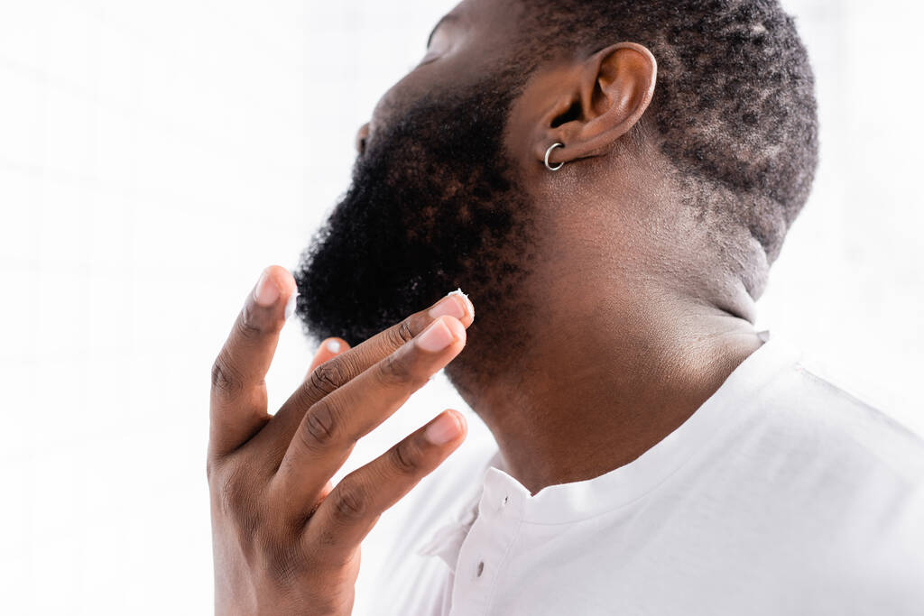 afro-amerykański człowiek stosujący lekarstwo na wzmocnienie wzrostu brody - Zdjęcie, obraz