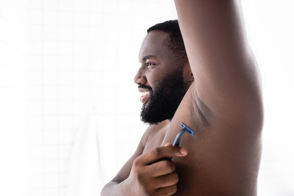 mosolygós afro-amerikai férfi kezével fel borotválkozás hónalj - Fotó, kép