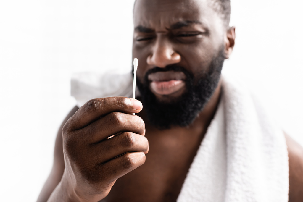 hombre afro-americano mirando el palo de la oreja con asco - Foto, imagen