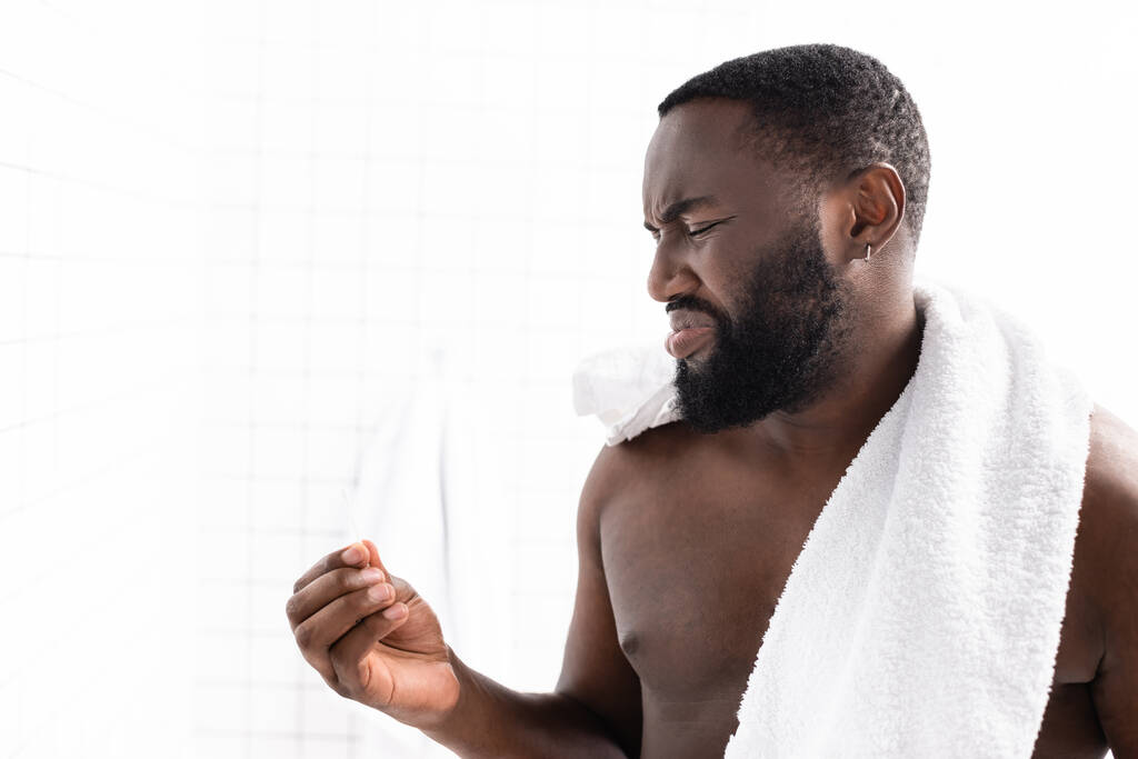 афроамериканський чоловік дивиться на вухо палицею з огидою
 - Фото, зображення