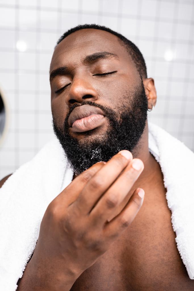 retrato del hombre afroamericano usando cura para fortalecer el crecimiento de la barba - Foto, imagen