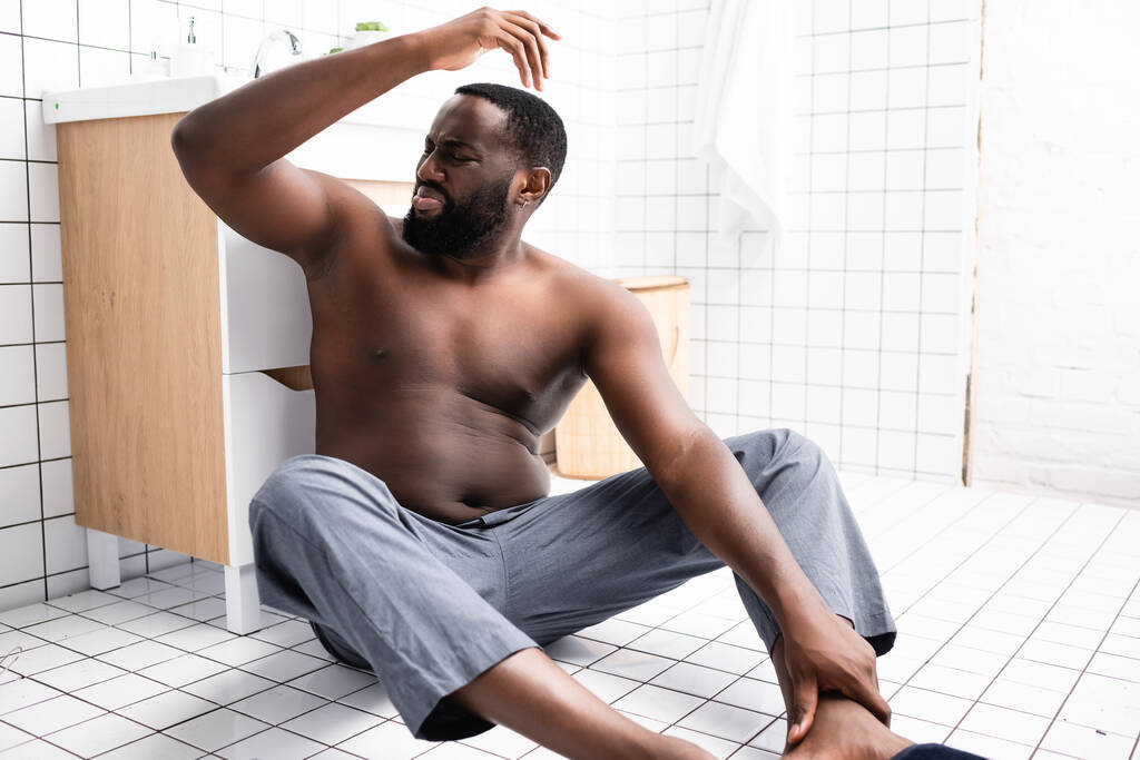 afro-americký muž s rukou na podlaze a páchnoucí podpaží - Fotografie, Obrázek
