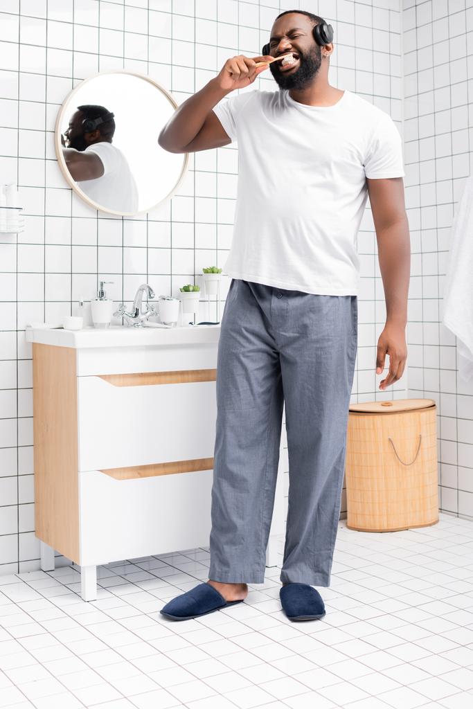 tutta la lunghezza dell'uomo afro-americano con cuffie lavarsi i denti  - Foto, immagini