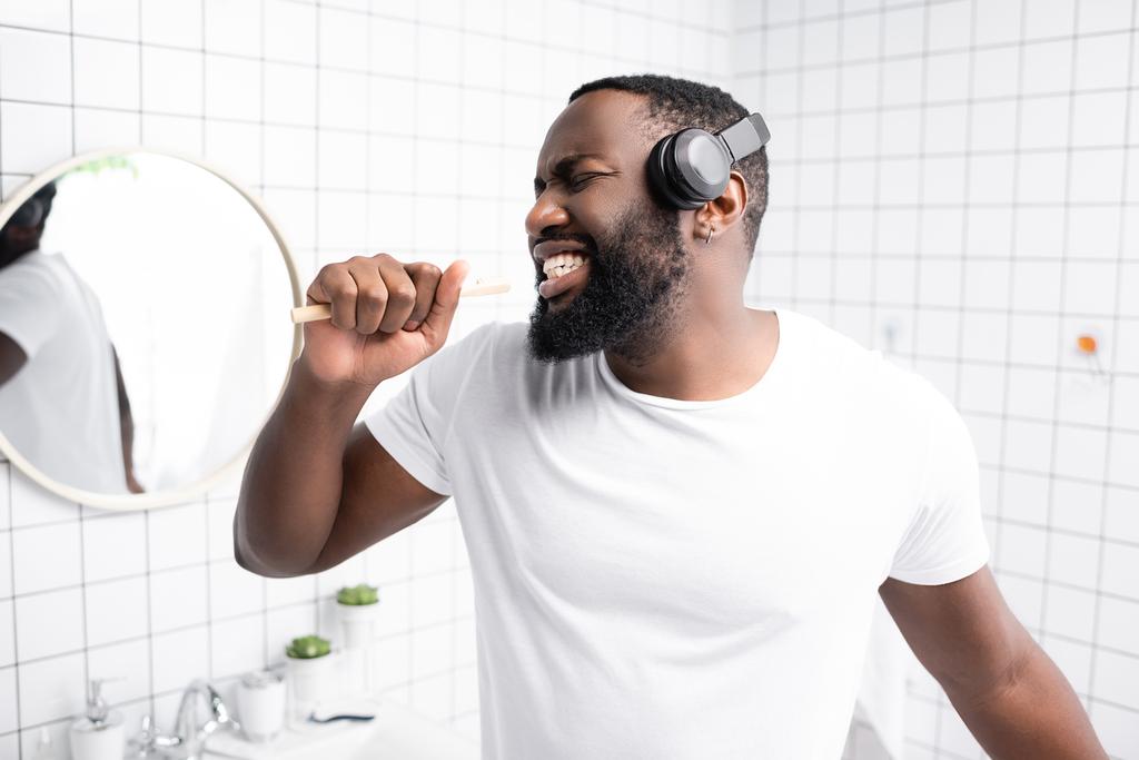homme afro-américain avec écouteurs chantant dans la brosse à dents - Photo, image
