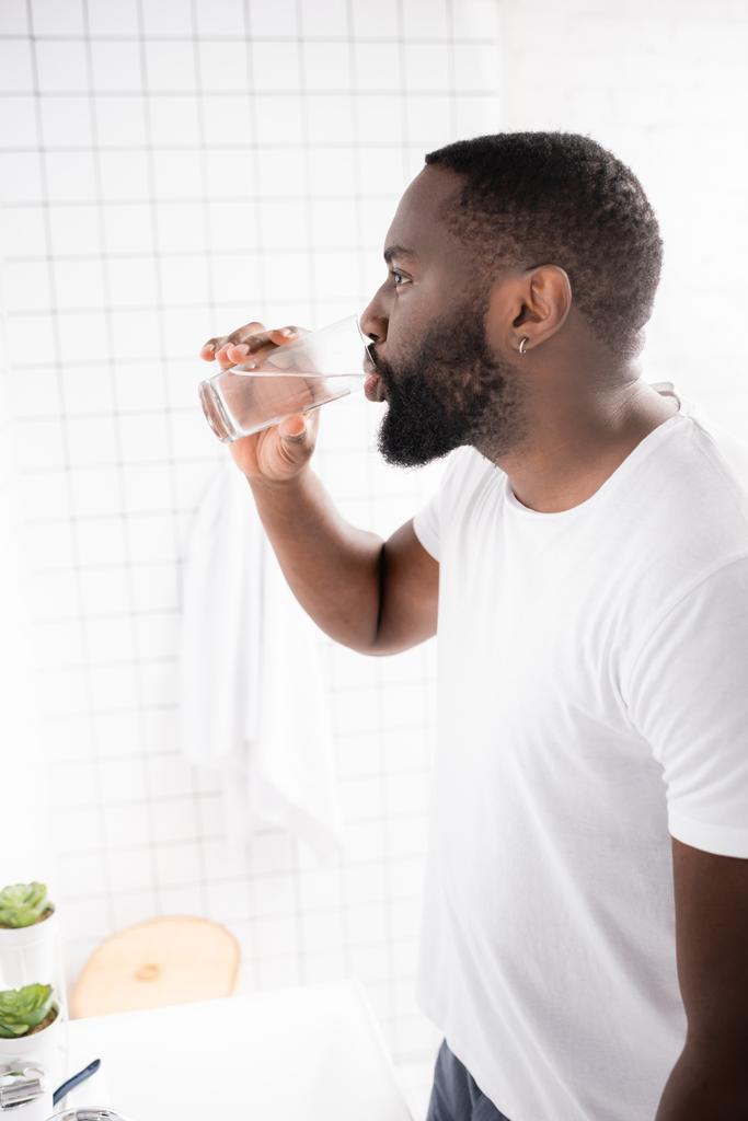 widok z boku afro-amerykańskiego człowieka wody pitnej  - Zdjęcie, obraz