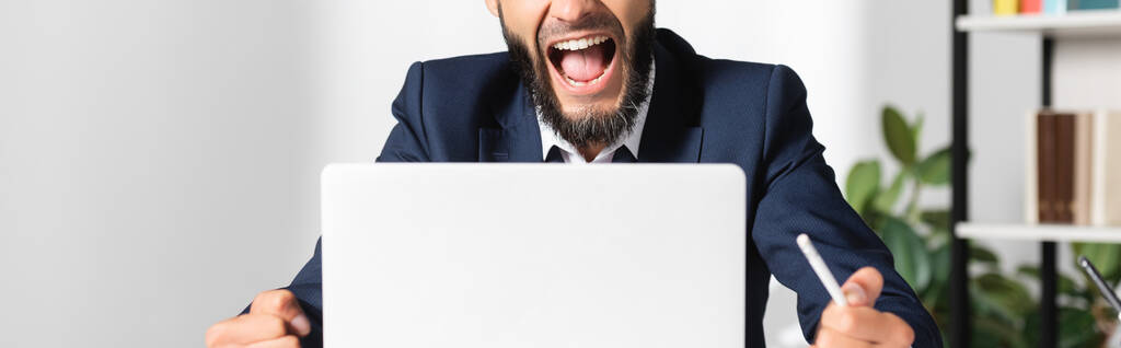 Rajallinen näkymä stressaantunut liikemies kynällä huutaa lähellä kannettavaa toimistossa, banneri  - Valokuva, kuva