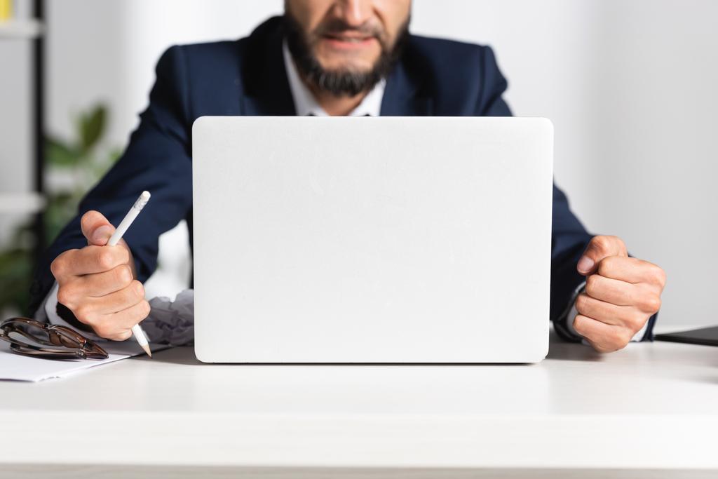 Обрізаний вид стресового бізнесмена, що тримає зламаний олівець біля окулярів і ноутбука на офісному столі
  - Фото, зображення
