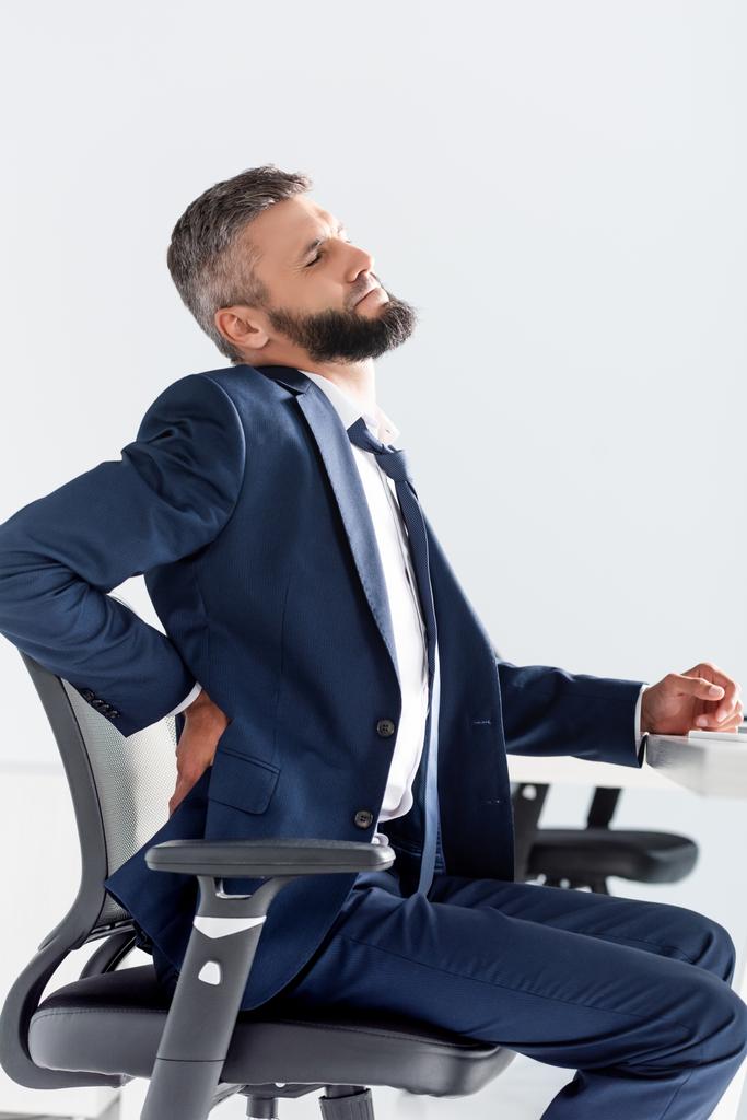 Podnikatel ve formálním oblečení trpí bolestí zad u stolu v kanceláři  - Fotografie, Obrázek