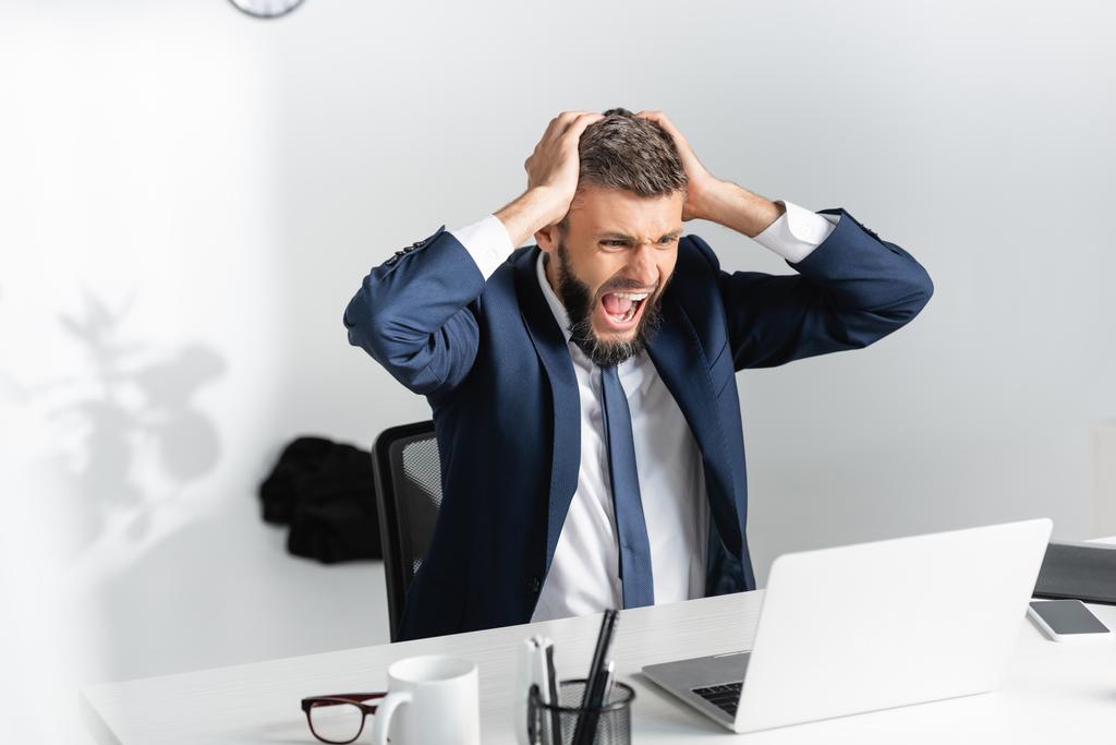 Empresario gritando y tocando la cabeza durante la crisis nerviosa en la oficina  - Foto, imagen