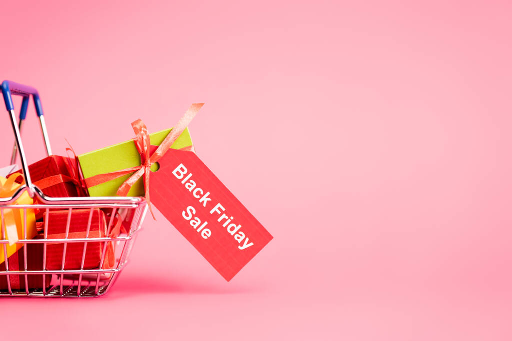 cesta de la compra con regalos y etiqueta roja con letras en rosa, concepto de viernes negro  - Foto, imagen