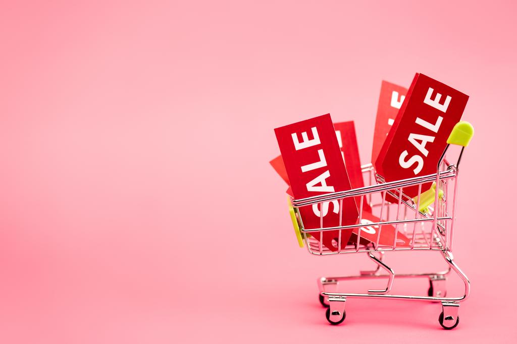 rote Etiketten mit Black Friday Sale Schriftzug im Einkaufswagen auf rosa  - Foto, Bild