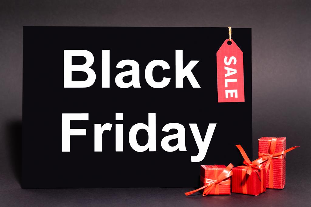 tabliczka z czarnym piątkowym napisem i tagiem sprzedaży w pobliżu prezentów na ciemnym tle - Zdjęcie, obraz