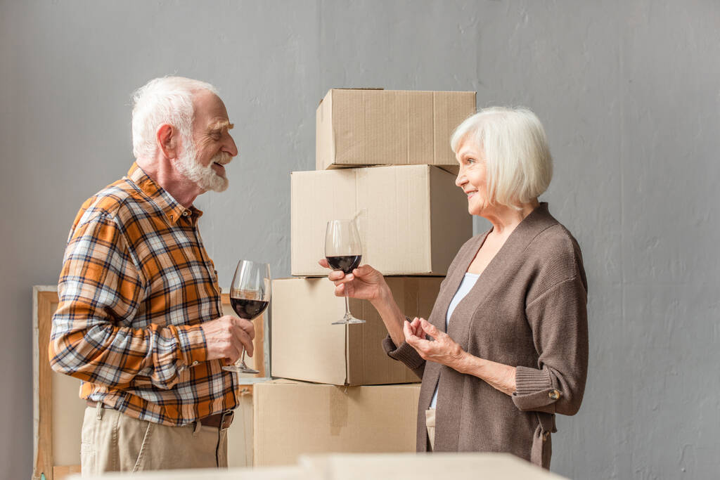 щаслива старша пара святкує переїзд в новий будинок з келихами вина
 - Фото, зображення