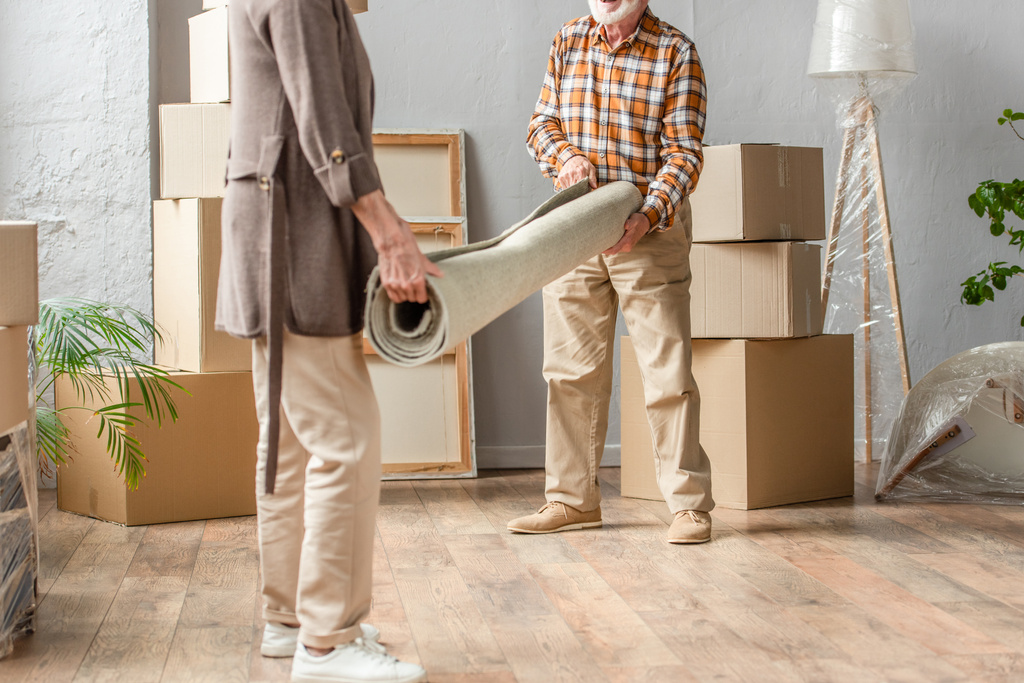 обрезанный вид на старшую пару подвижной ковер в новом доме, движущаяся концепция - Фото, изображение