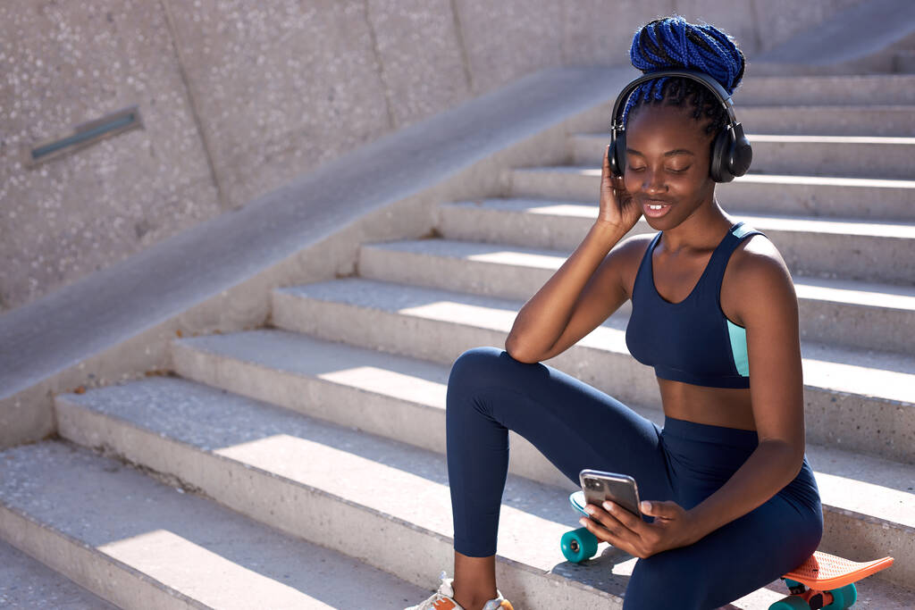 Sevimli siyahi kadın spor sonrası dinlenirken müzik dinliyor. - Fotoğraf, Görsel
