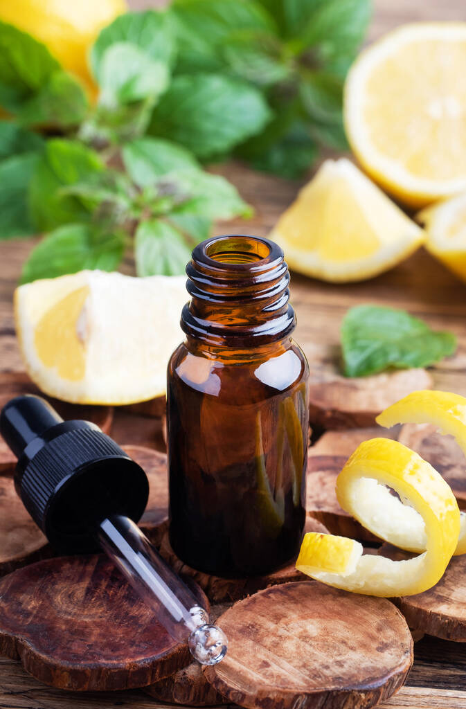 レモン柑橘系の果物エッセンシャルオイルとミント、素朴な木の背景にアロマセラピーオイル天然有機化粧品 - 写真・画像