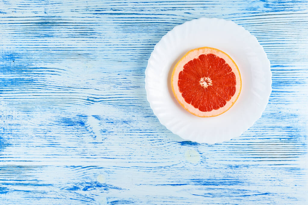 Čerstvé grapefruit na bílém talíři na dřevěném pozadí - Fotografie, Obrázek