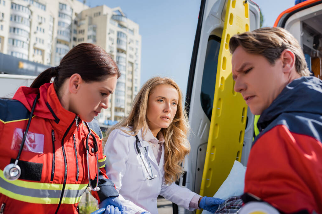 Szelektív fókusz az orvos nézi mentős közelében mentős autó szabadban  - Fotó, kép
