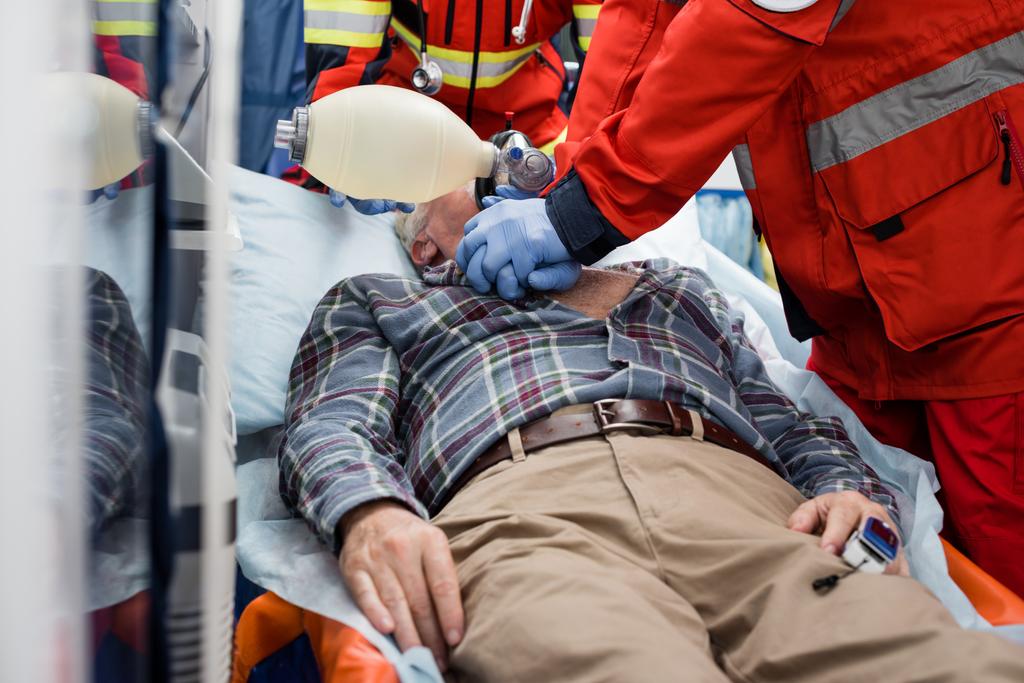 Выборочный фокус парамедиков, делающих кардиолегочную реанимацию с маской мешкового клапана больному пациенту во время оказания первой медицинской помощи  - Фото, изображение