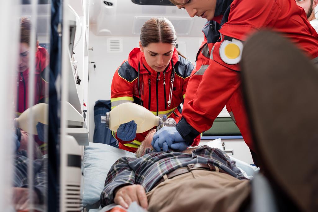 Concentration sélective des ambulanciers paramédicaux en uniforme effectuant une réanimation cardiopulmonaire à l'homme pendant les premiers soins  - Photo, image