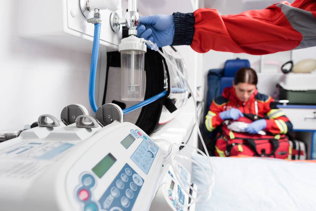Selective focus of paramedic using nebuliser near equipment in ambulance auto  - Photo, Image