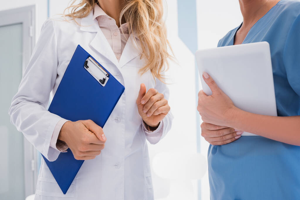 Обрезанный вид врача, держащего планшет рядом с медсестрой с цифровым планшетом в клинике  - Фото, изображение