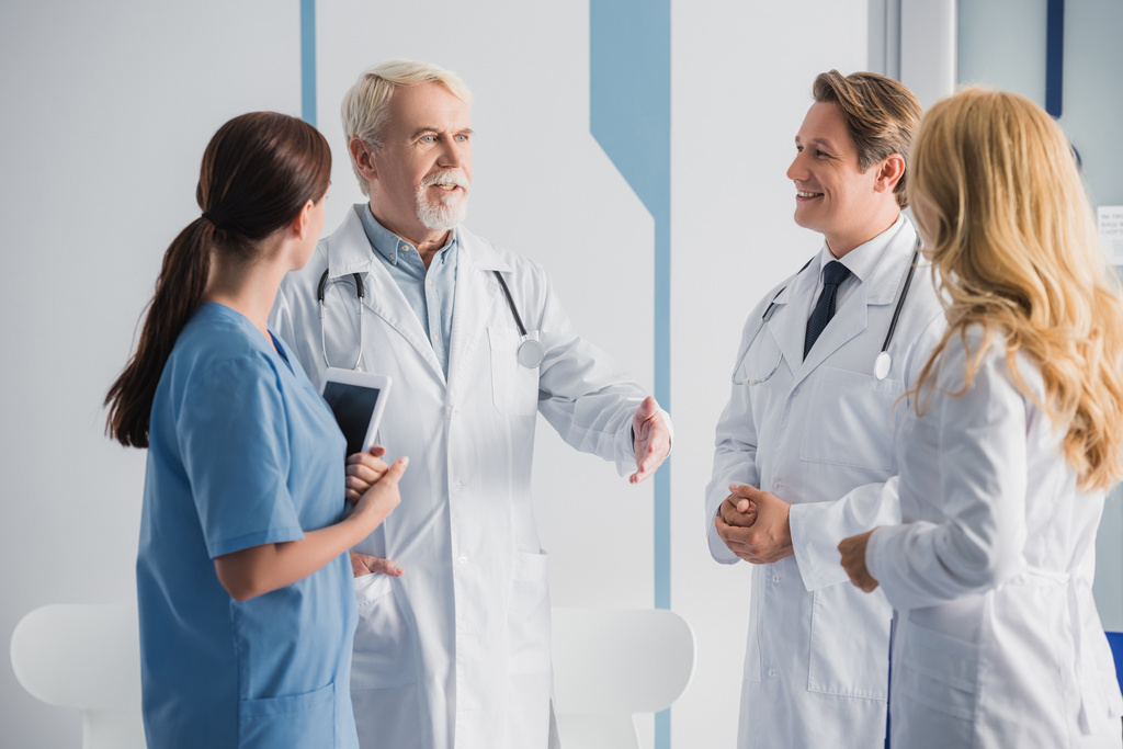 Selektywne skupienie się starszego lekarza rozmawiającego z kolegami ze szpitala  - Zdjęcie, obraz