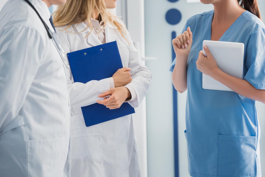 Обрезанный вид медсестры, держащей цифровой планшет рядом с врачами с буфером обмена  - Фото, изображение