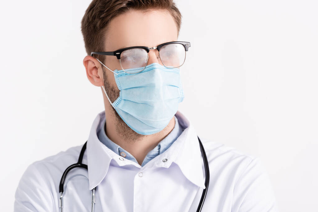 Orvosportré sztetoszkóppal és párolt szemüveggel, fehér alapon izolált orvosi maszkot viselve - Fotó, kép