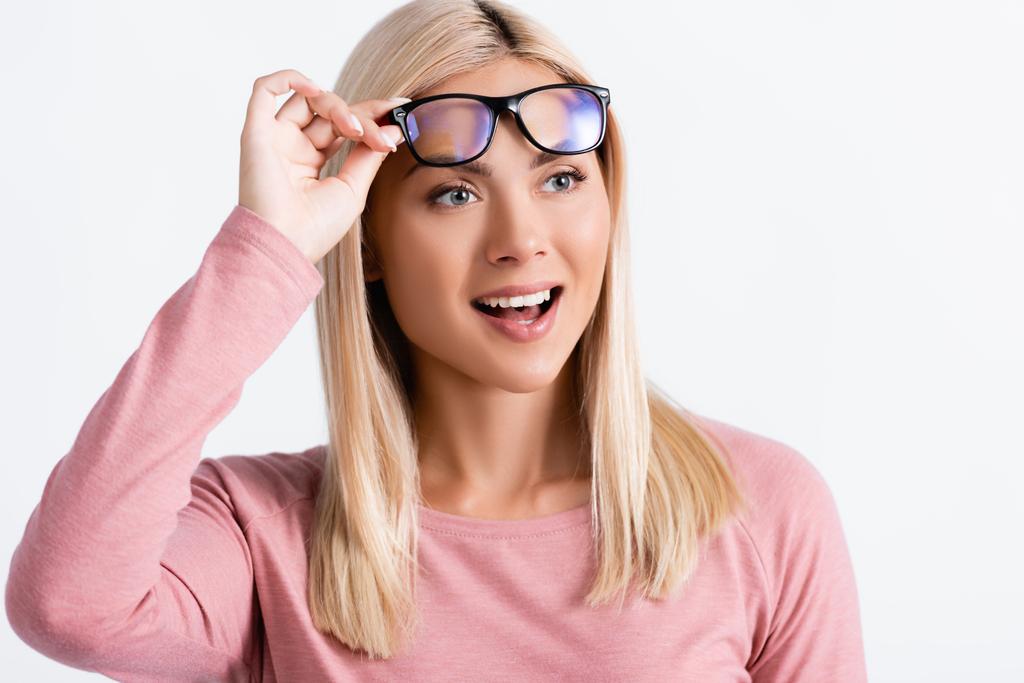 Aufgeregte junge Frau schaut weg, während sie eine graue Brille hält - Foto, Bild