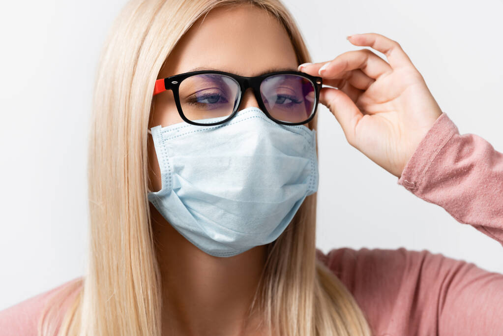 Squint nainen lääketieteellinen naamio koskettaa silmälasit eristetty harmaa - Valokuva, kuva