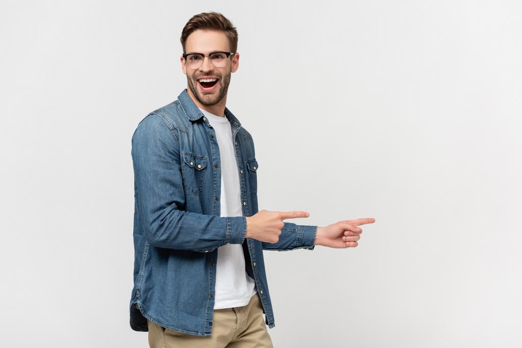 Χαρούμενος άντρας με γυαλιά που δείχνει με τα δάχτυλα απομονωμένα στο γκρι. - Φωτογραφία, εικόνα