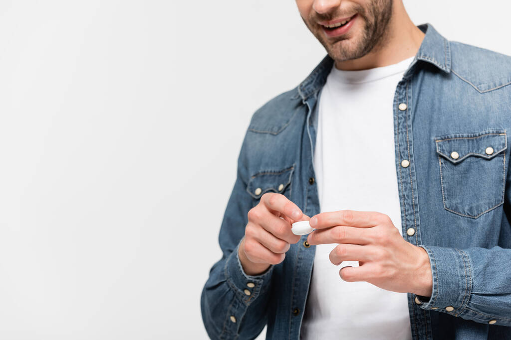 Box with contact lens in hands of smiling man on blurred background isolated on grey - Photo, Image