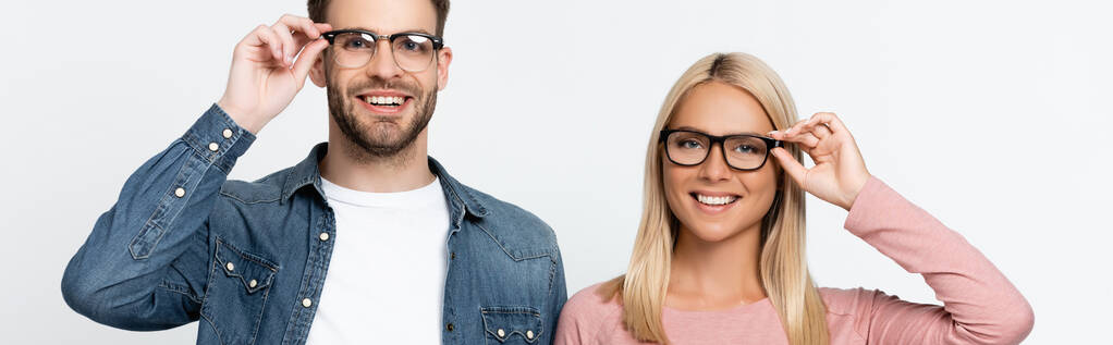 Usmívající se pár dotýkající se brýlí izolovaných na šedé, banner  - Fotografie, Obrázek