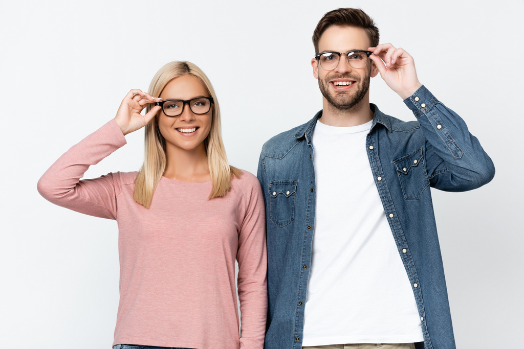 Молода пара посміхається на камеру, торкаючись окулярів ізольовано на сірому
 - Фото, зображення