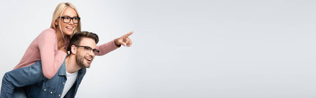 Gözlüklü, gülümseyen bir kadın, gri pankartta izole edilmiş sevgilisini parmağıyla işaret ediyor.  - Fotoğraf, Görsel
