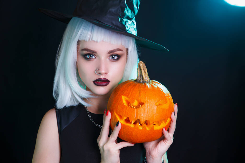 Halloween strega sexy con una zucca intagliata su sfondo scuro - Foto, immagini