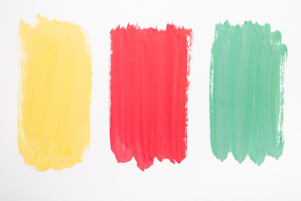 top view of abstract colorful green, yellow and red paint brushstrokes on white background - Photo, Image